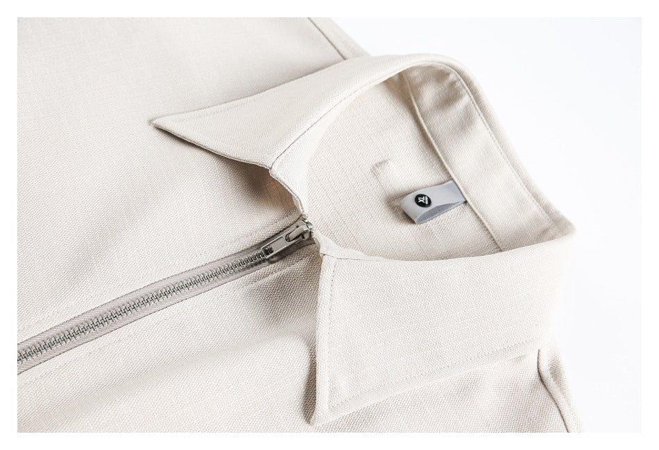 Close-up of an ivory garment collar, small sewn label, and silver zipper.