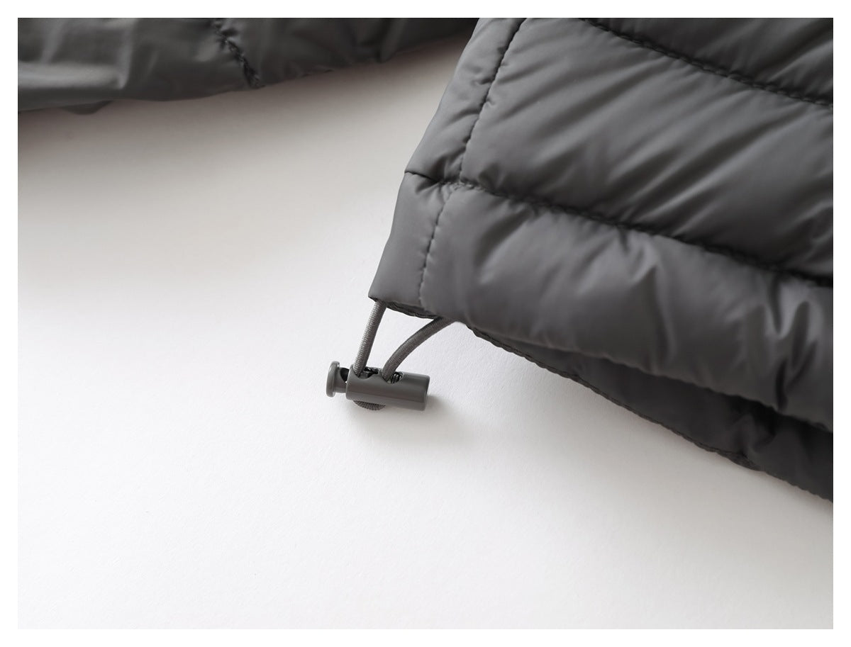 Close-up of a dark gray quilted jacket hem with an adjustable drawcord and toggle.