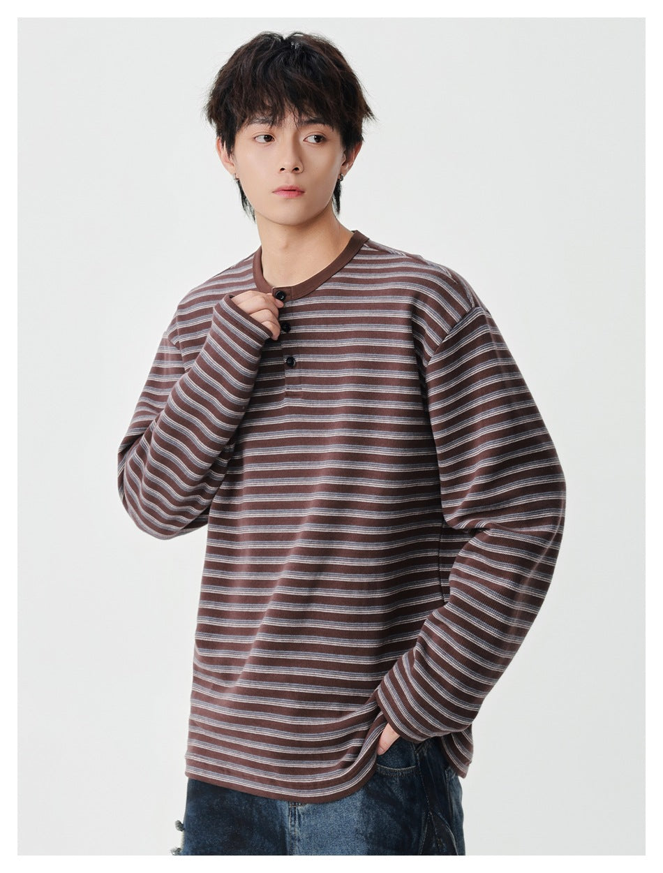 Model wearing a brown and gray striped long-sleeve henley, holding the collar placket.