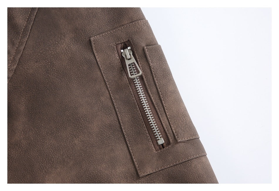 Close-up of a brown jacket's silver zipper pocket and stitched rectangular panel.