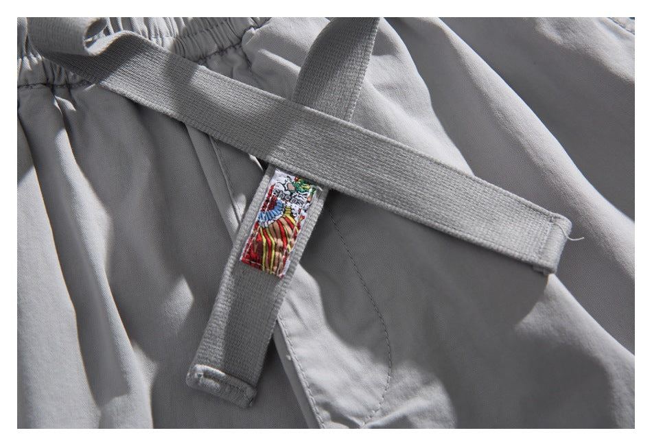 Close-up of gray webbing straps and a small colorful sewn-on label on the shorts.