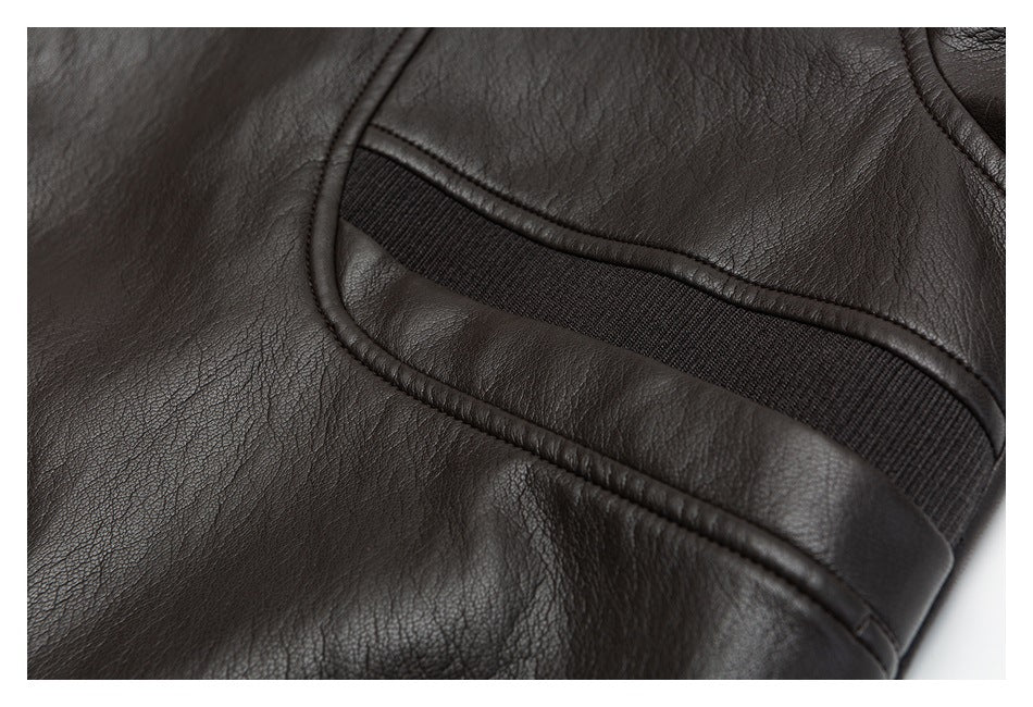 Close-up of a dark brown jacket panel with curved piping and a black ribbed inset.