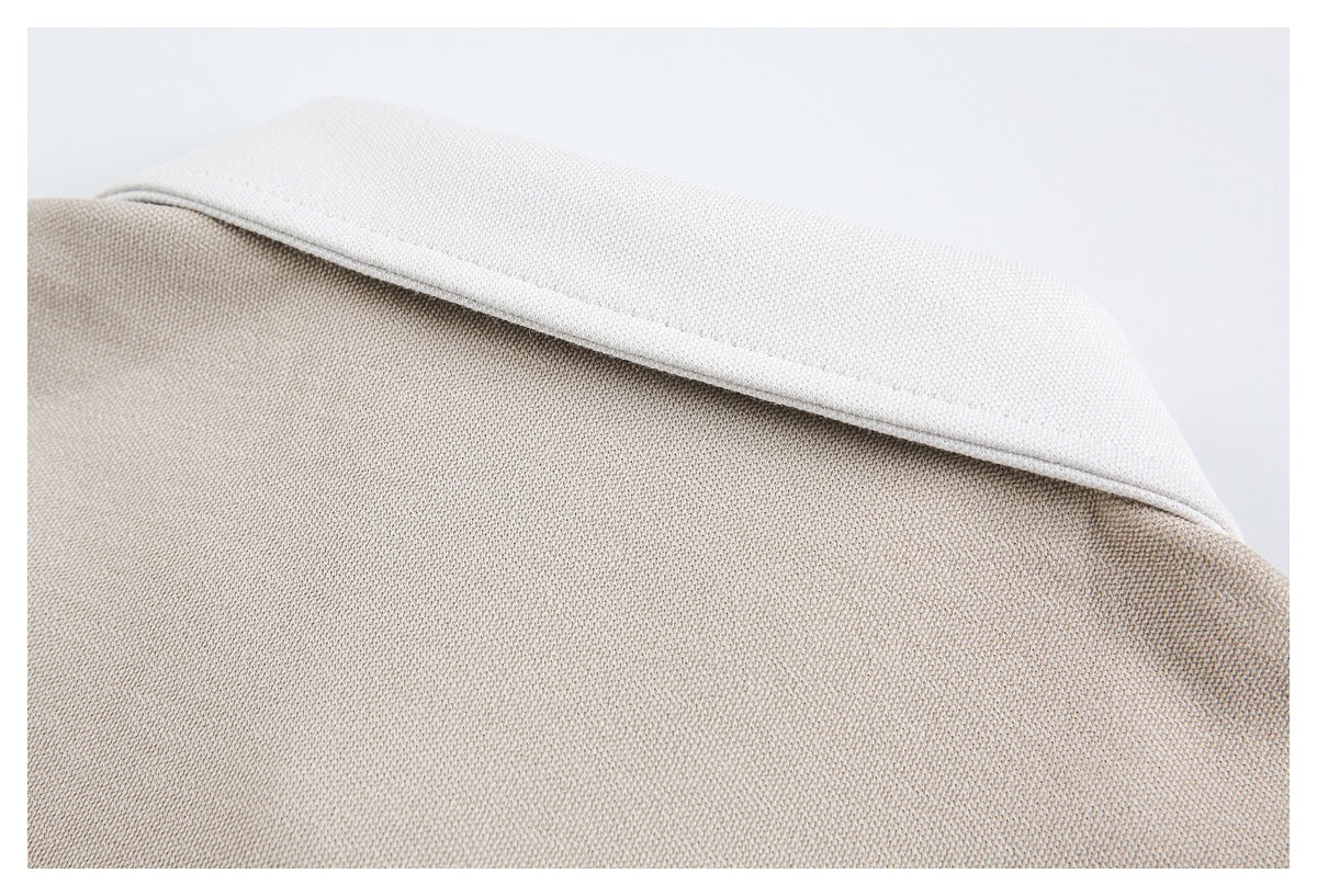 Close-up of a white collar against beige knit fabric.