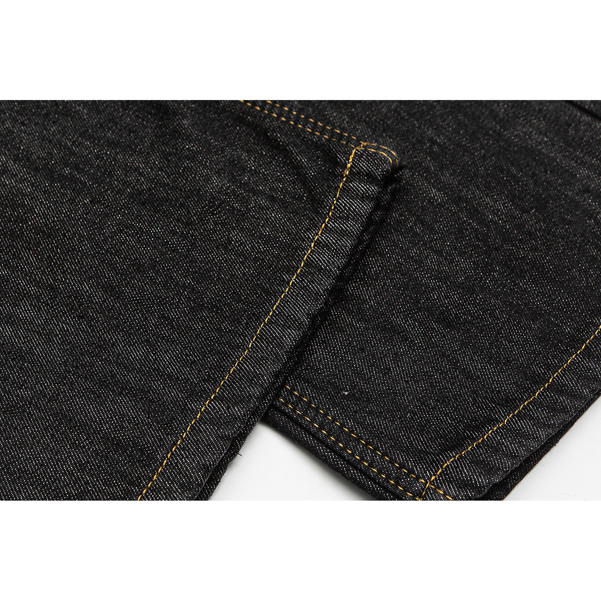 Close-up of dark indigo jeans showing a folded leg edge and contrasting golden stitching.