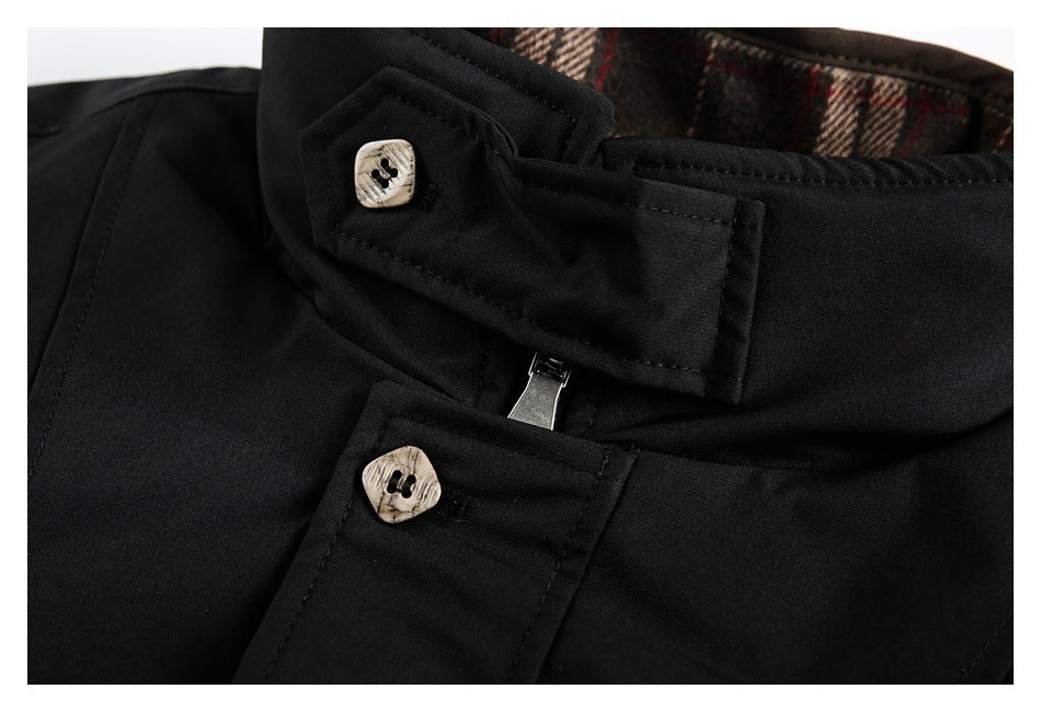 Close-up of a black jacket's collar fastening, patterned buttons and plaid lining.