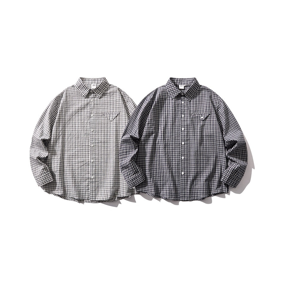 Two long-sleeve button-up shirts laid flat, one light gray and one dark gray, both in plaid with chest pockets.