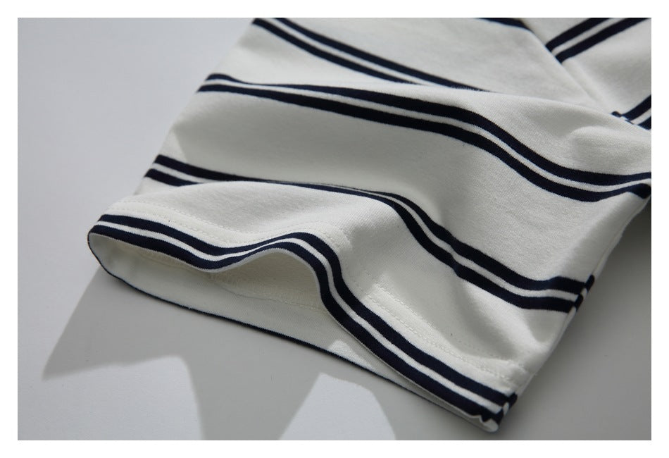 Close-up of a cream garment's finished edge with navy stripes and visible stitching.
