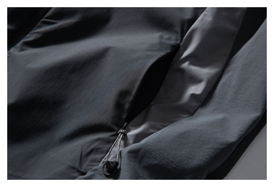 Close-up of a charcoal jacket pocket opening with a zipper and corded pull.