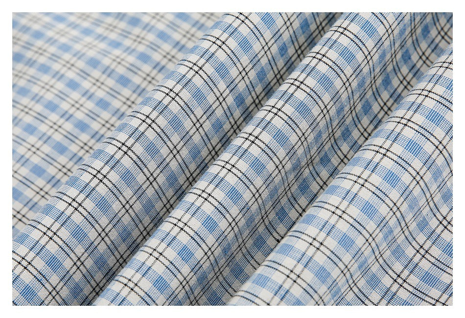 Close-up of light blue, white, and black plaid shirt fabric draped in soft folds.