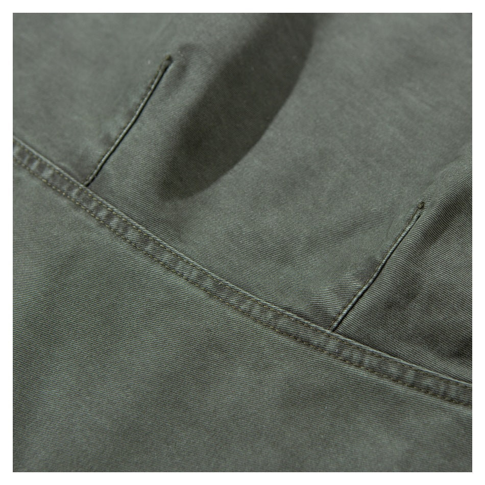 Close-up of olive-gray trouser fabric showing a pocket edge and stitched seam.