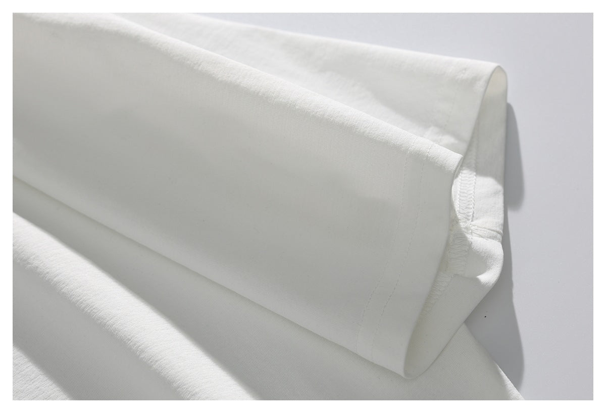 Close-up of a white garment sleeve folded back, showing the seam and overlocked edge.