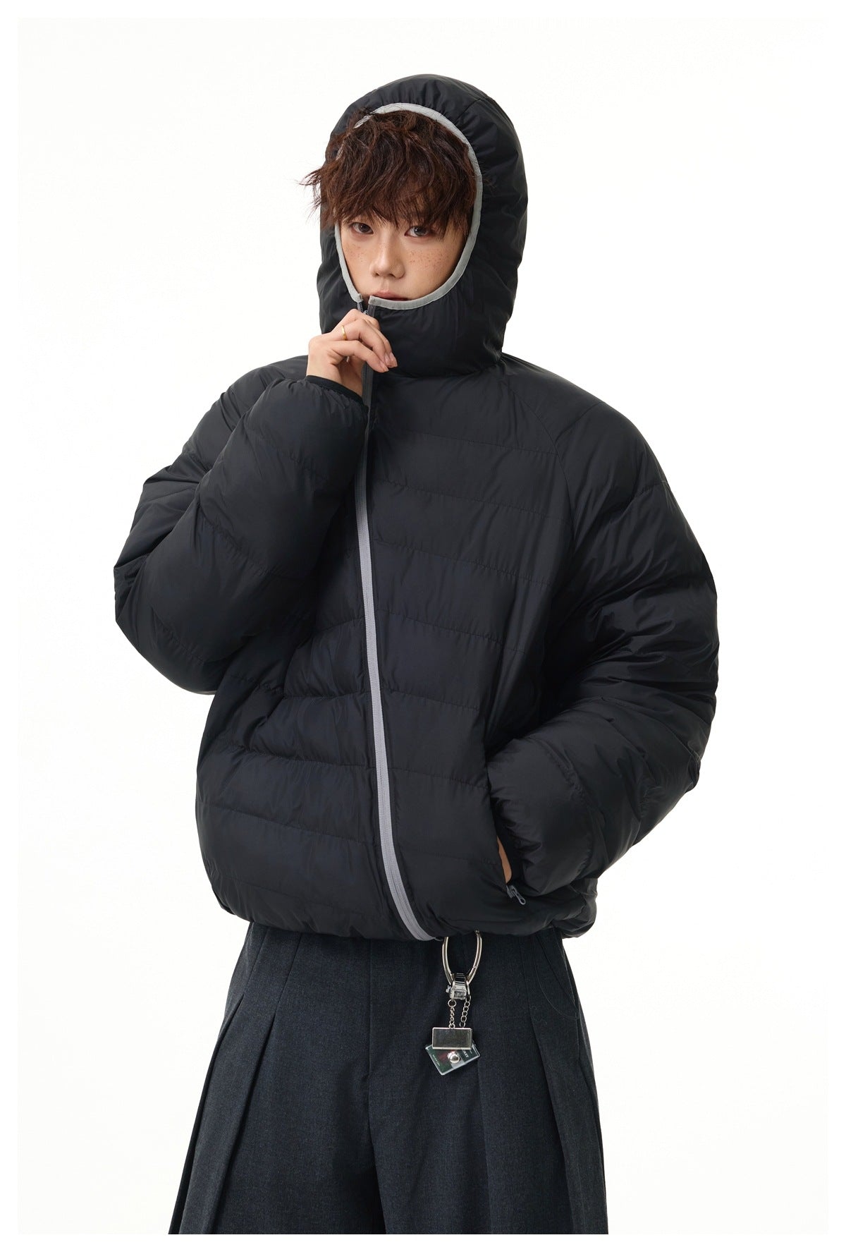 Model wearing a black horizontally quilted puffer jacket with an oversized hood and light gray trim around the face.