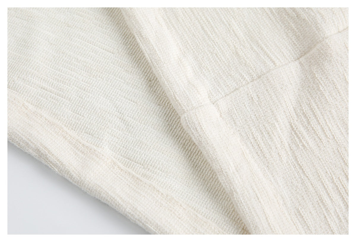 Close-up of an ivory knit garment showing a wide ribbed band and fine knit texture.
