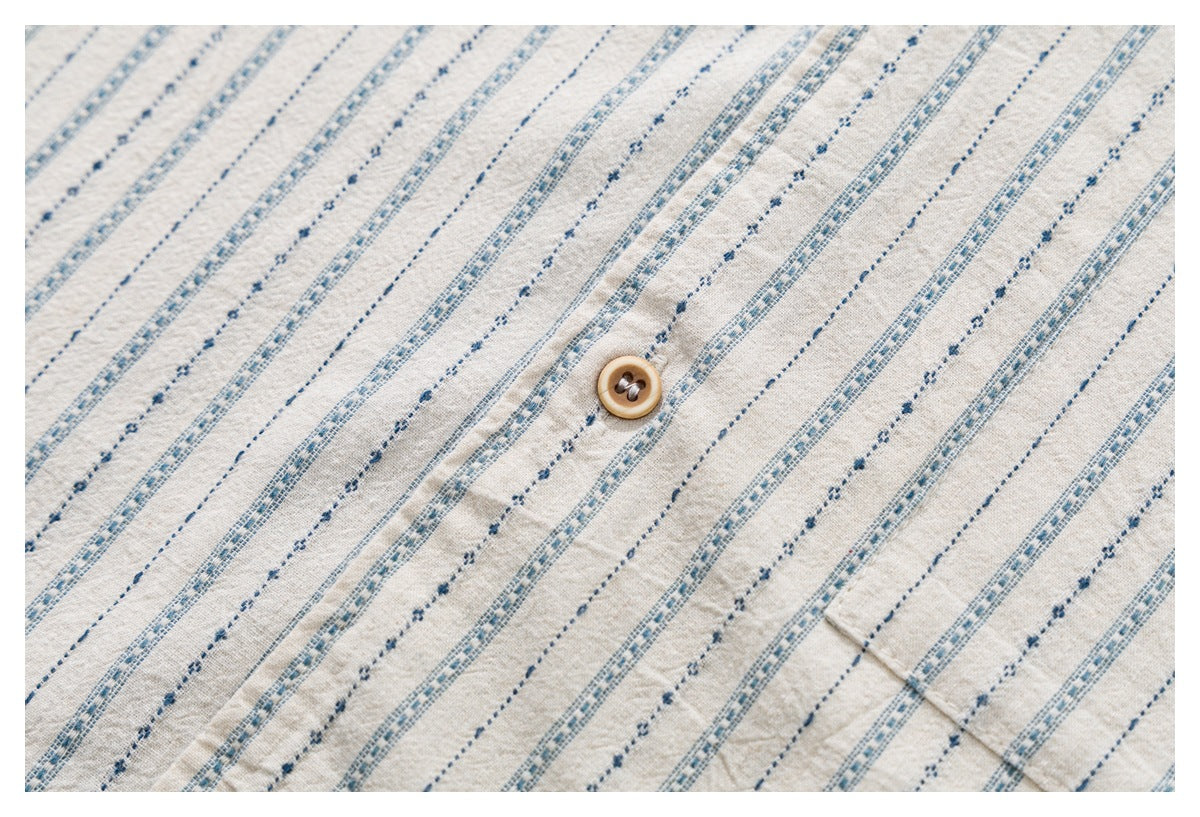 Close-up of the off-white shirt's blue and gray stripe pattern and a wooden button.