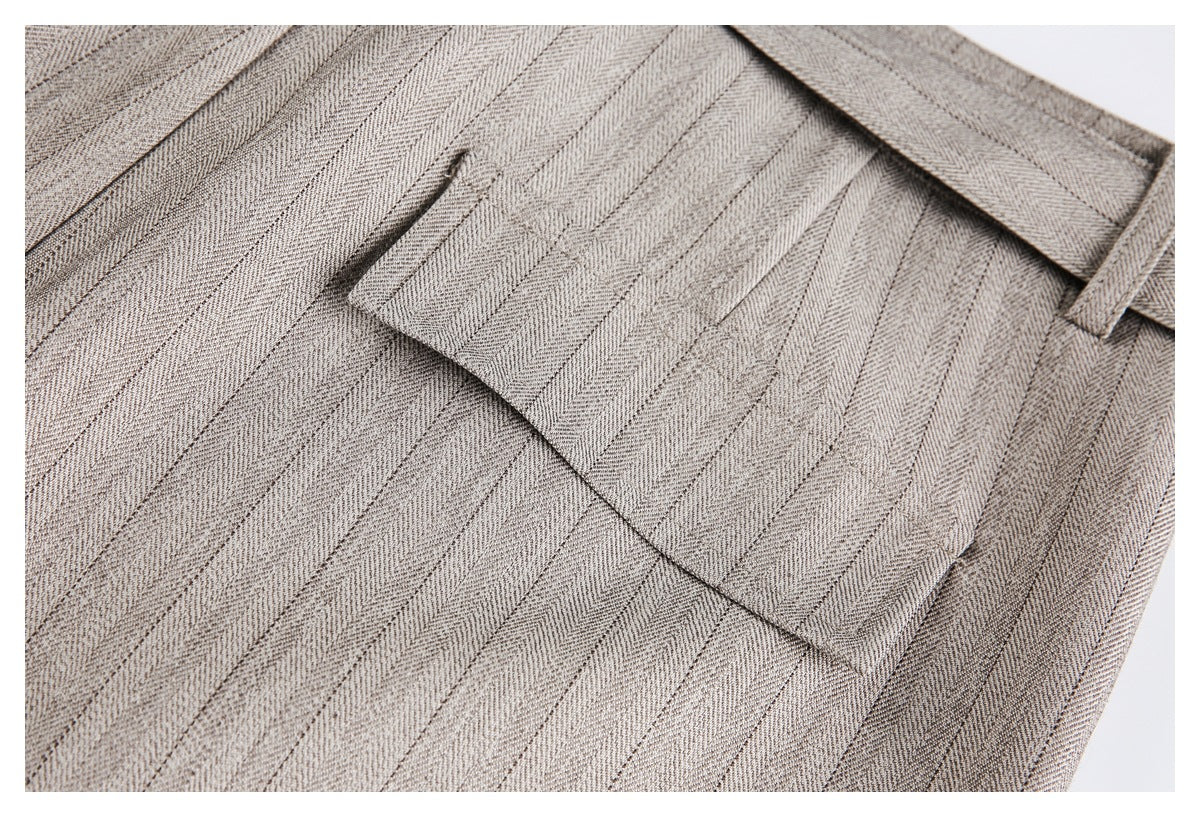 Close-up of beige-gray pinstriped trousers showing a flap pocket and belt loop.
