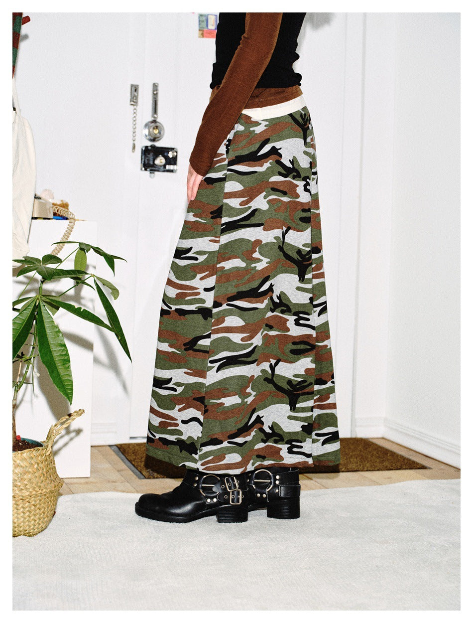 Side view of a person wearing a long camouflage A-line skirt with a brown top and black buckled boots