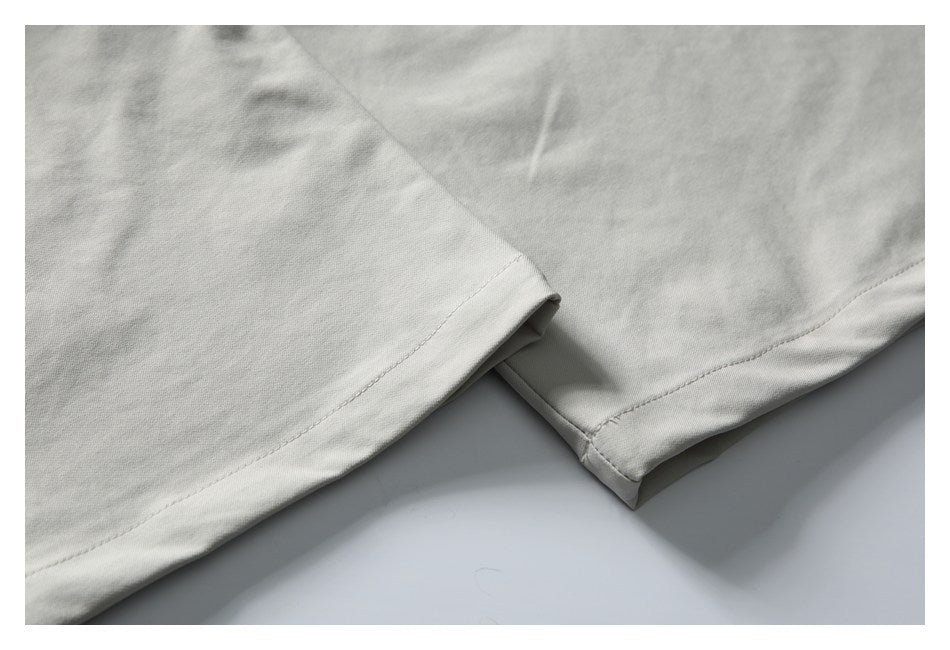 Close-up of the stitched hems of light gray trouser legs.
