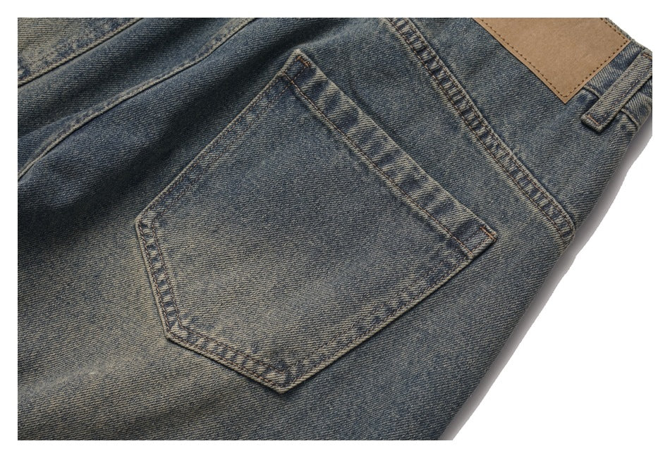 Close-up of a back pocket on faded blue jeans, showing contrast stitching and a blank tan leather patch.