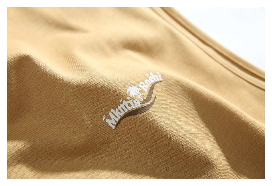 Close-up of the shirt's small white printed chest logo on sand-colored fabric.