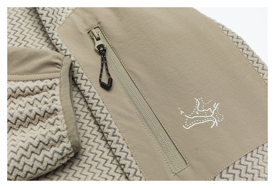 Close-up of a beige zippered chest pocket with a black pull cord and small white emblem on zigzag-patterned fabric.