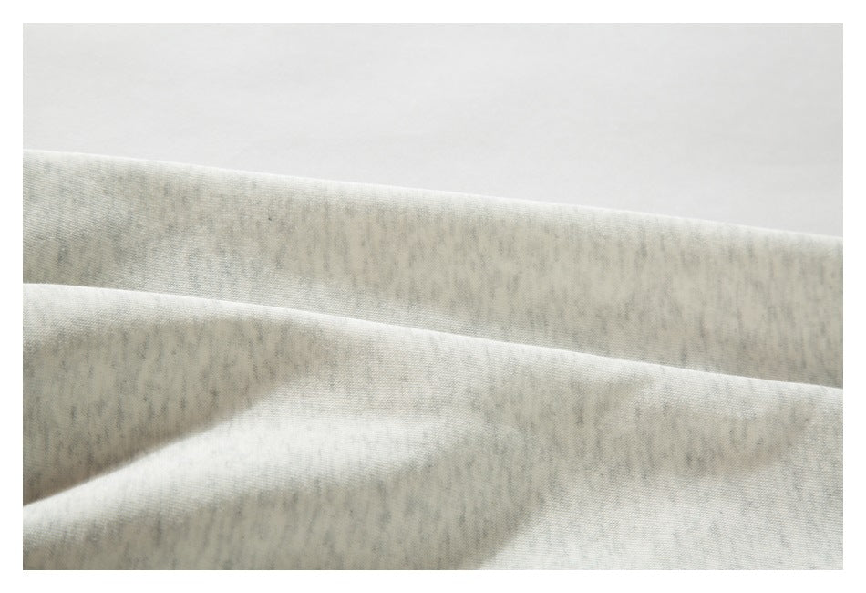 Close-up of pale gray and off-white marled fabric folded into soft ridges.