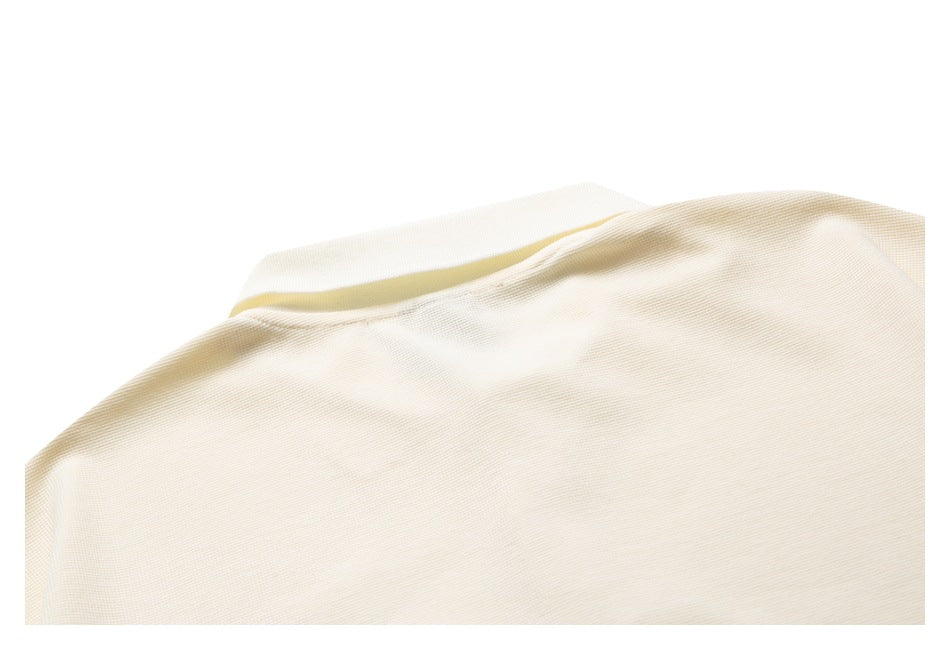 Close-up of cream fabric with a curved edge and narrow pale yellow inner trim.