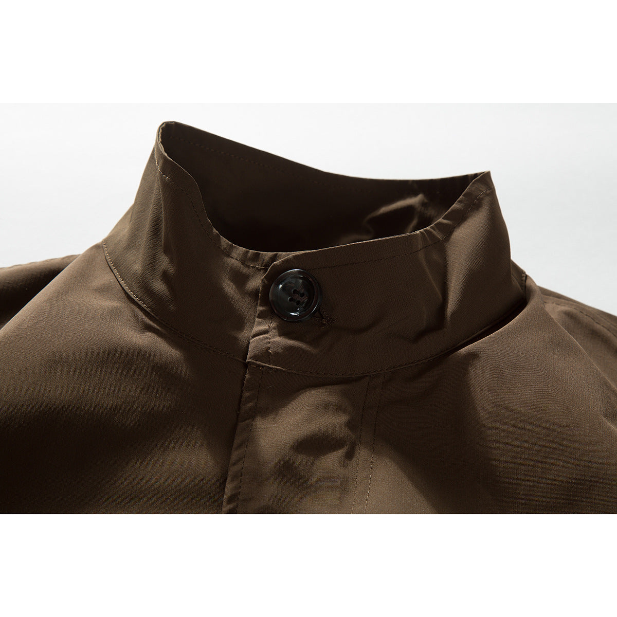 Close-up of a brown jacket's stand collar, black button, and front placket.