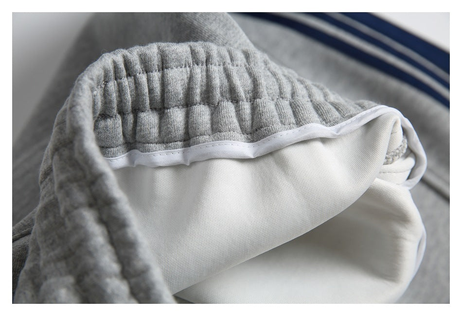Close-up of gray sweatpants showing the gathered elastic waistband and white inner lining.