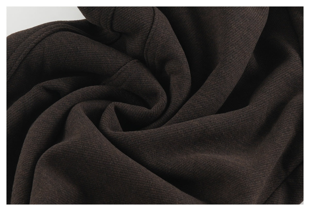 Extreme close-up of dark brown pants fabric, draped to show its surface texture.