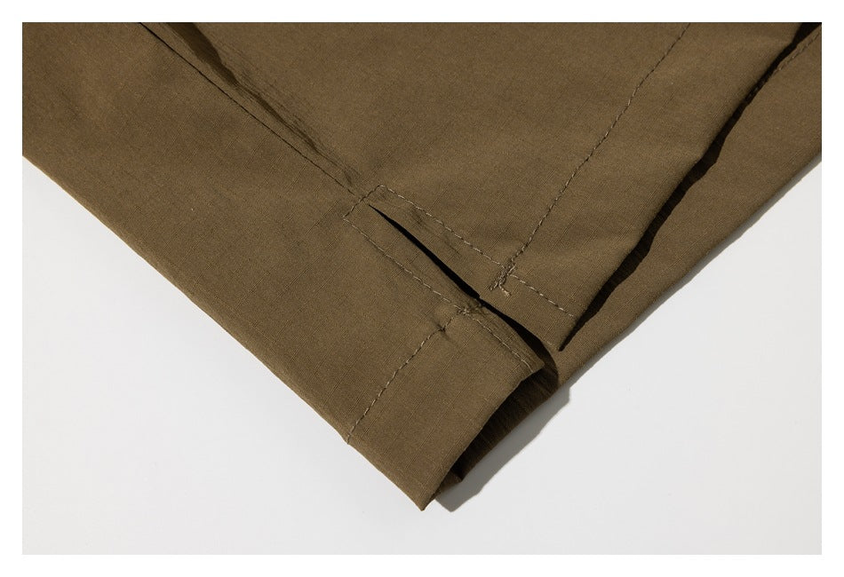 Close-up of an olive-brown garment hem with a side slit and stitched edge.