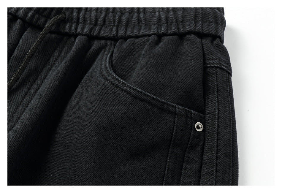 Close-up of a black pants pocket, elastic waistband, and metal rivet.