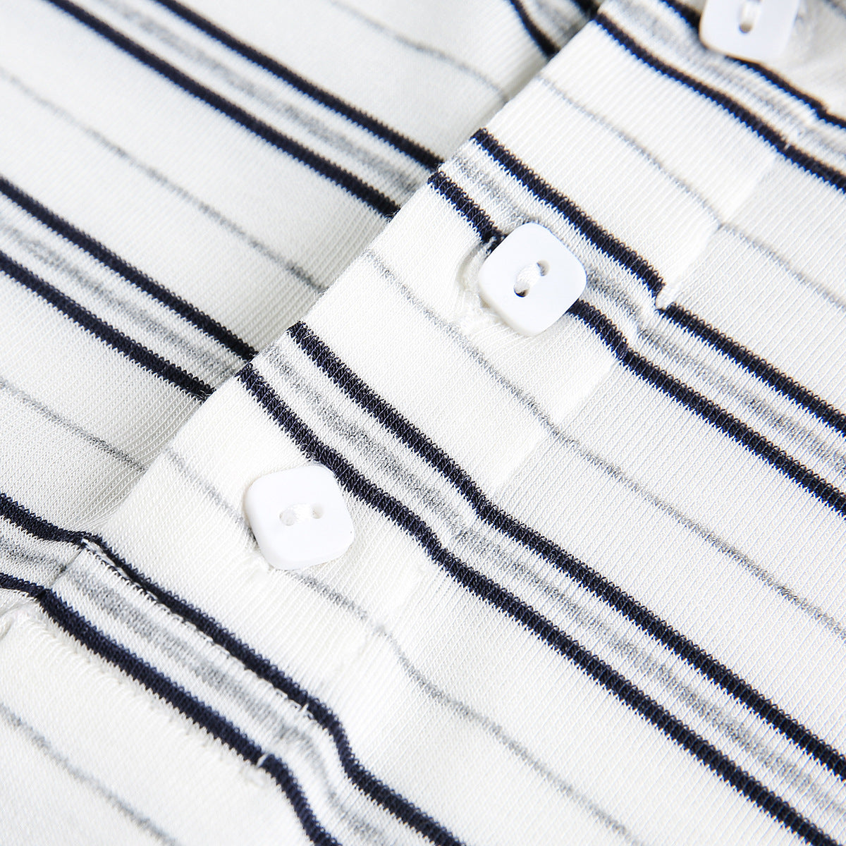 Close-up of white knit fabric with dark vertical stripes and small white buttons.