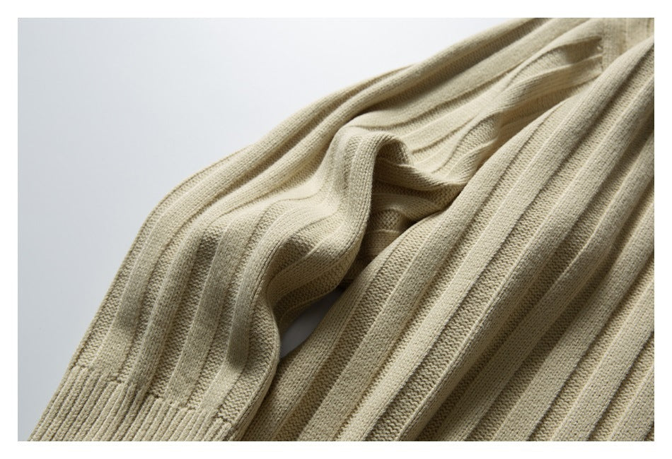 Close-up of a beige ribbed knit sweater draped to show its textured vertical stitch pattern.