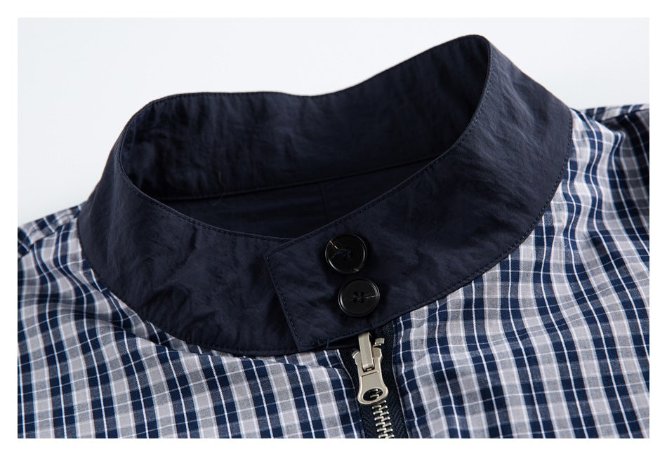 Close-up of a dark navy buttoned collar and zipper on a blue-and-white plaid jacket.