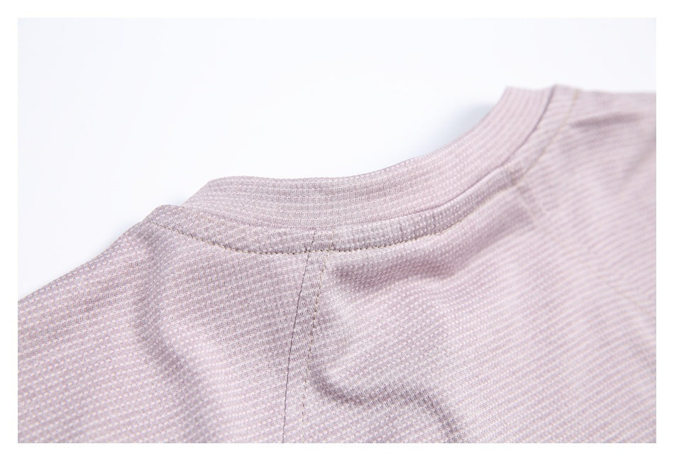 Close-up of a pale mauve patterned garment showing its rounded neckline and stitched collar seam.