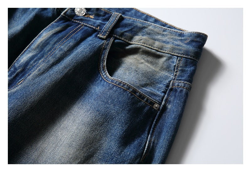 Close-up of blue faded jeans showing the waistband, fly, belt loop, and front pocket.