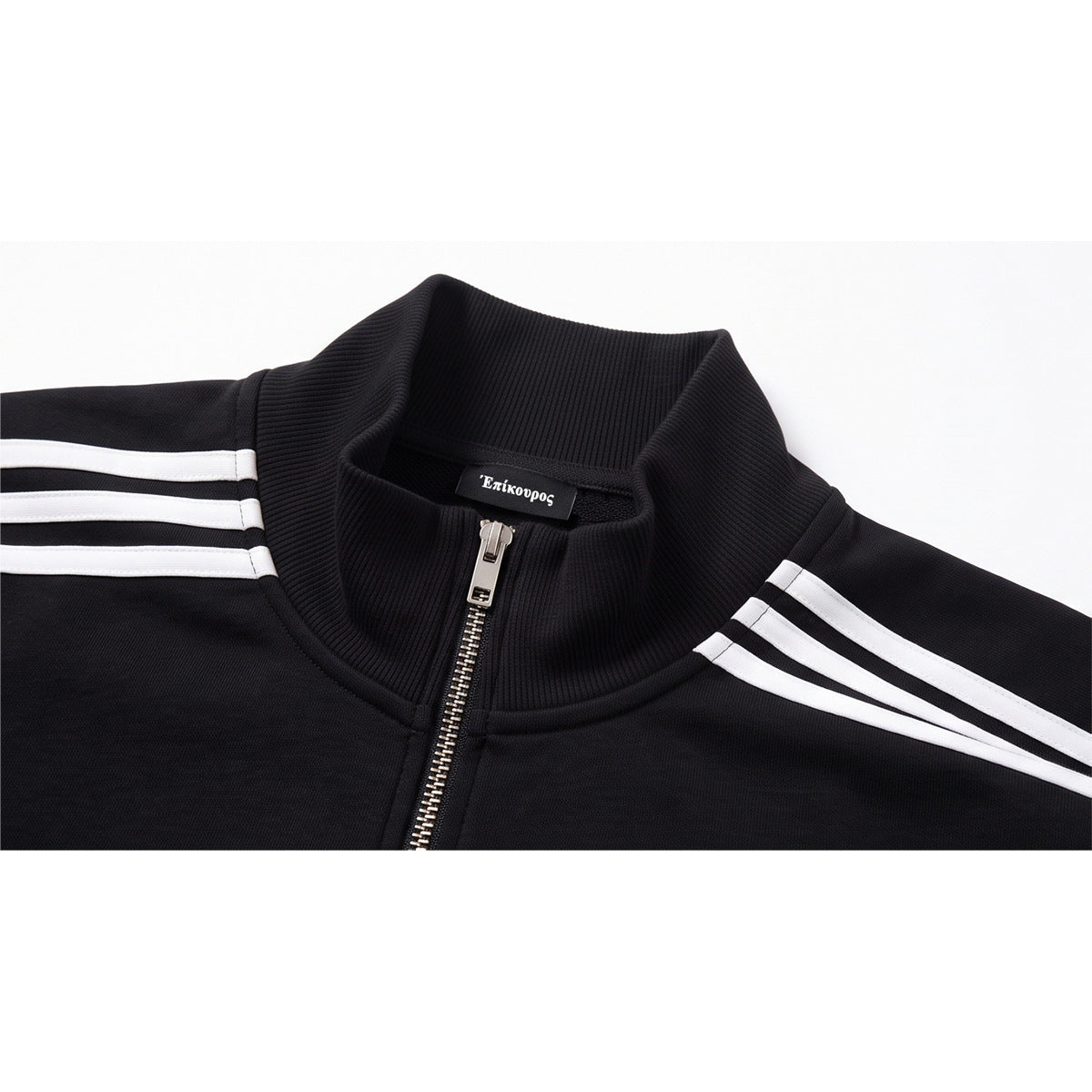 Close-up of a black track jacket's ribbed stand collar, metal zipper, and three white shoulder stripes.