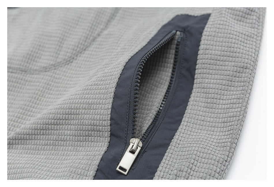 Close-up of an open dark zip pocket on gray textured fabric.