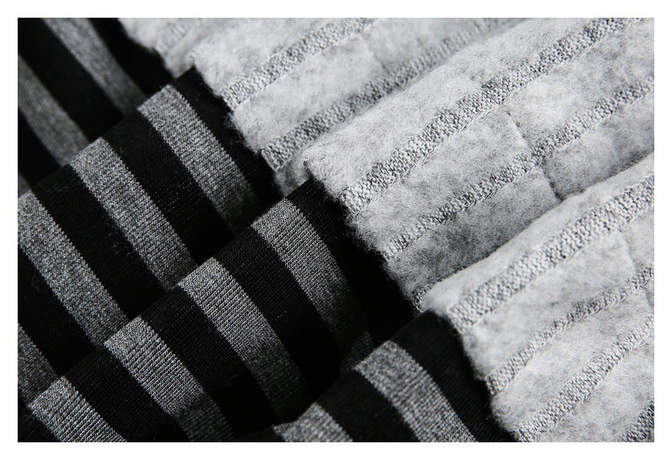 Close-up of black-and-gray striped fabric folded beside fuzzy light gray fabric with gray stripes.