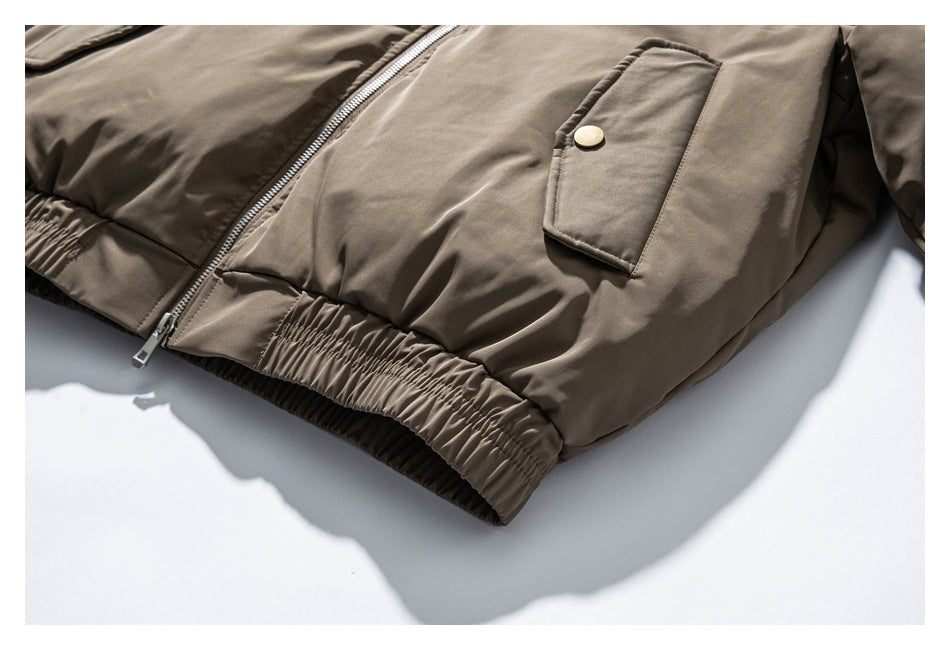 Close-up of a taupe jacket's silver front zipper, flap pocket with gold-tone snap, and gathered hem.
