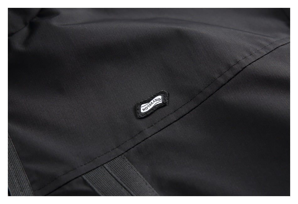 Close-up of a small black-and-white NO BRAND patch on black jacket fabric.