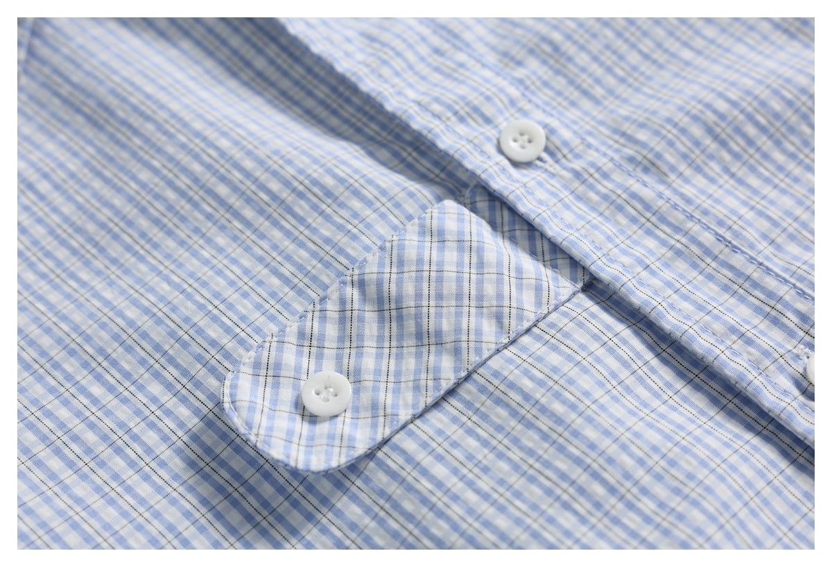 Close-up of a white button on the placket of a blue-and-white checked shirt.