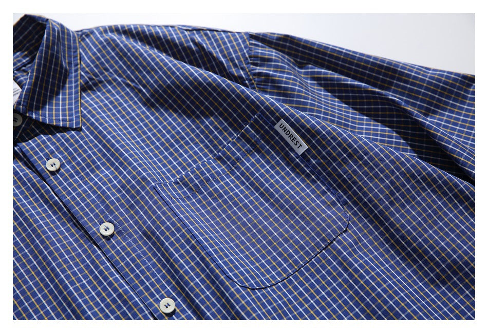 Close-up of the blue plaid shirt front, showing its button placket and single chest pocket.