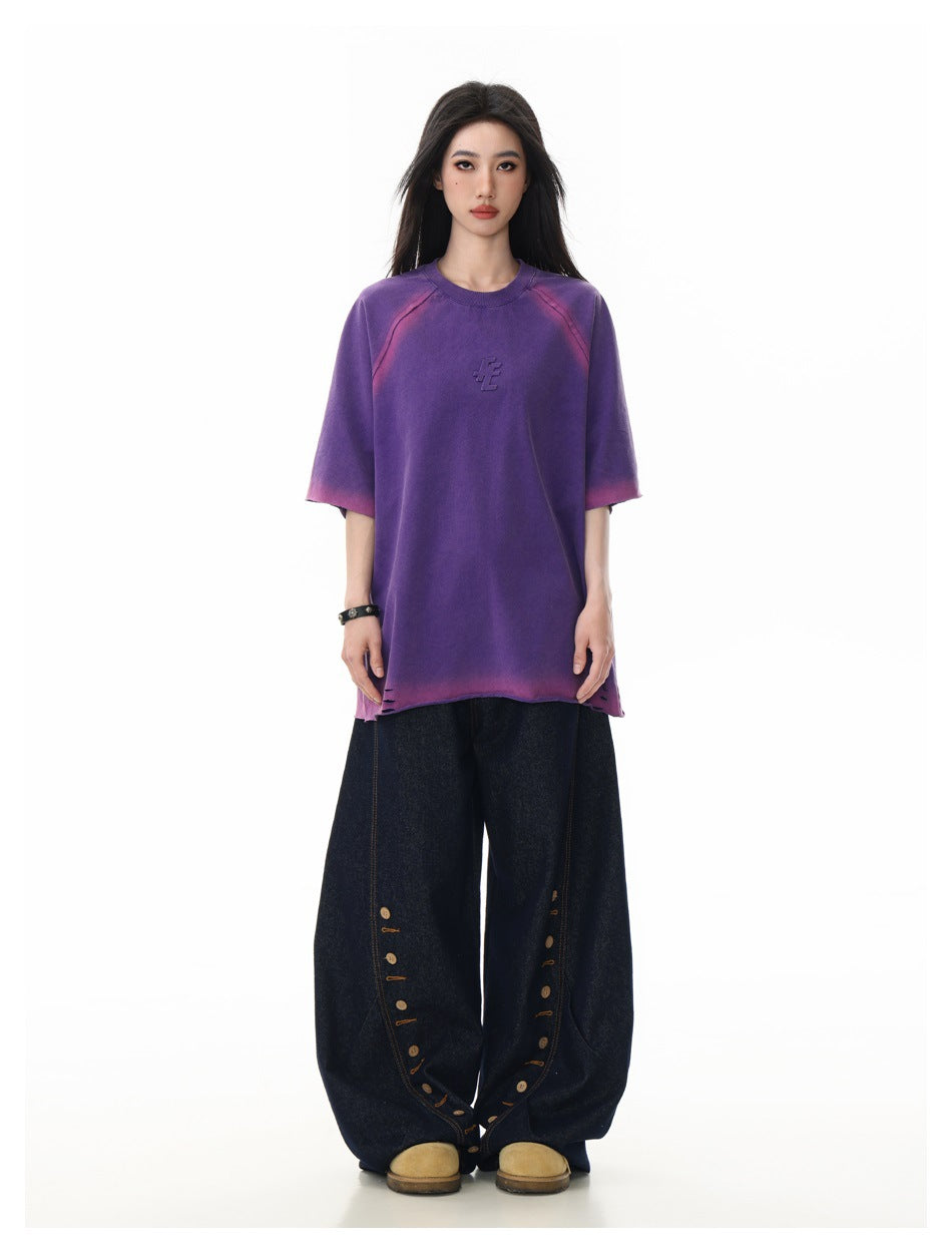 Model wearing the purple oversized raglan T-shirt with pink gradient edges and wide dark denim pants, full-length view