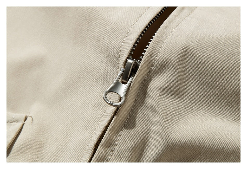Close-up of a partially open metal zipper on beige fabric.