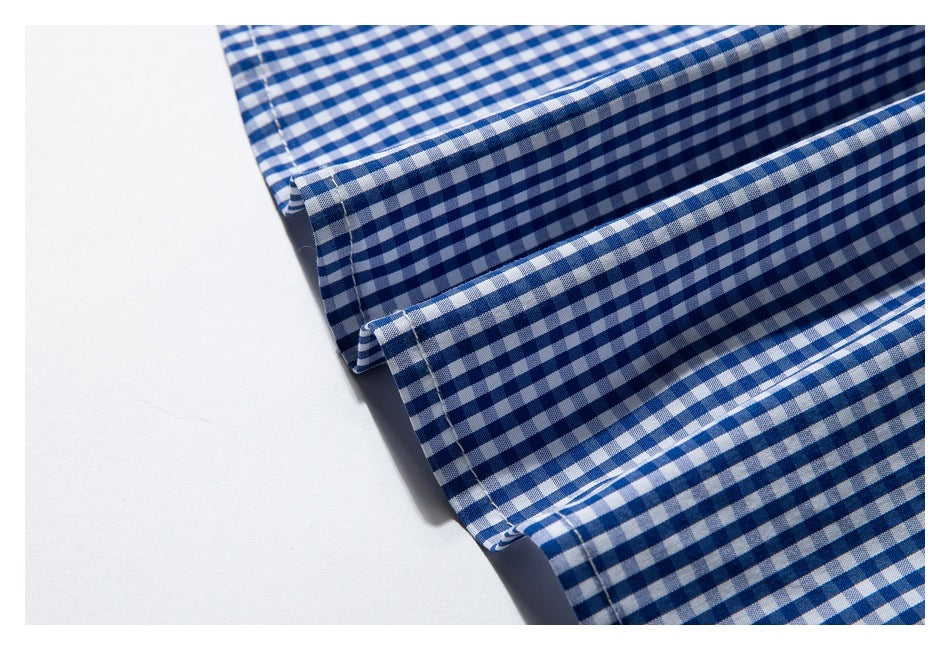 Close-up of the stitched edge and folded hem of blue-and-white gingham fabric.