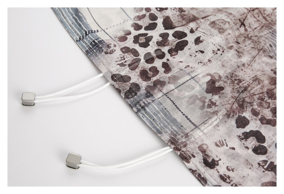 Close-up of a printed hem with two white drawcords and gray cord locks.