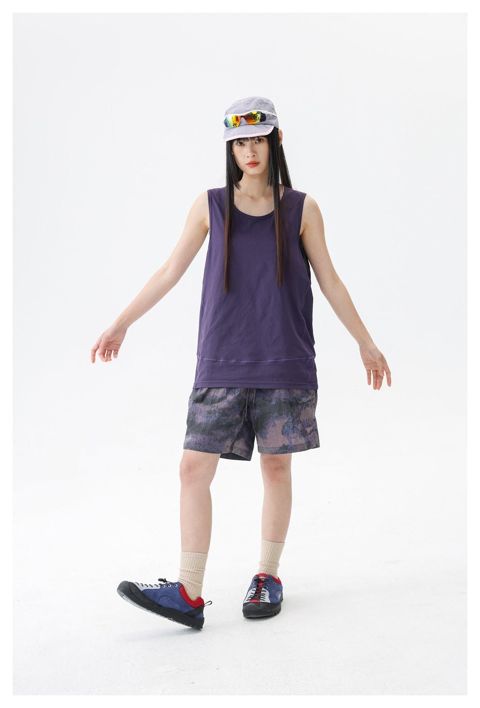 Full-length front view of a model wearing a dark purple sleeveless top and purple-gray patterned shorts.