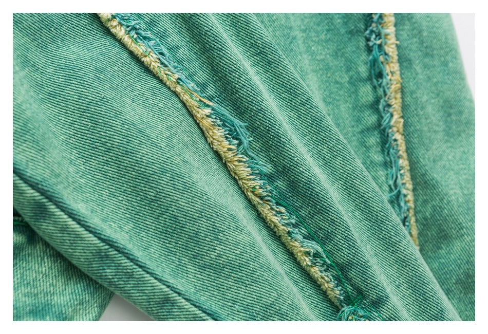 Close-up of teal denim panels and a seam edged with yellow-and-teal frayed threads.