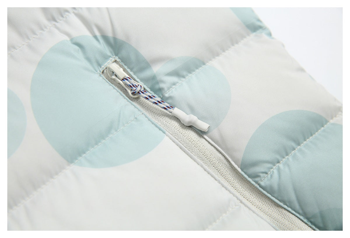 Close-up of a white pocket zipper with a patterned pull cord on a pale aqua circle-print puffer jacket.